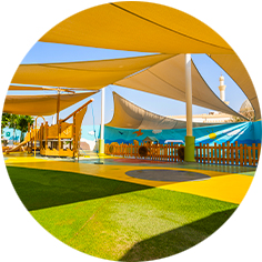 A children's playground with yellow umbrellas and yellow grass.