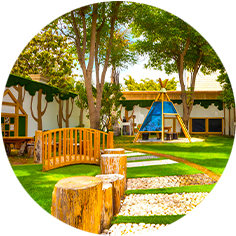 A circular image of a playground with trees and a teepee.