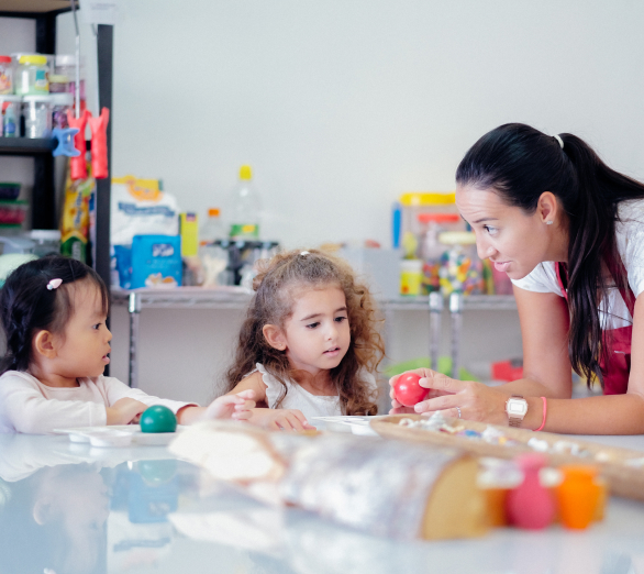 A group of children in a playroom with a teacher.