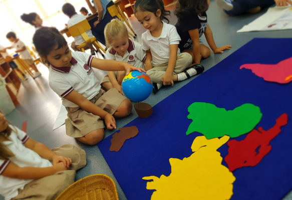 A group of children playing with a globe in a classroom.