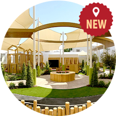 A modern outdoor playground with wooden structures, shaded areas, and greenery in a circular design, labeled with a 