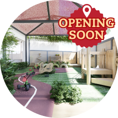 Outdoor children’s play area with toys, play equipment, artificial grass, and a sign that says “Opening Soon” at the top right.